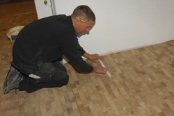 Rudi passt das letzte Parkettstck ein.  Fertig!