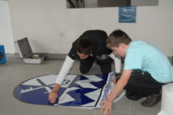 Jetzt wird es spannend. Die Firma Werbetechnik Jentges aus Reifferscheid  klebt die Wappenfolie auf den vorbereiteten Boden. 