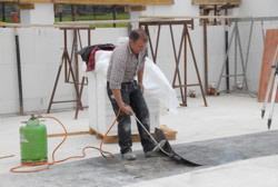 H. probiert die neue "Schuhsohlen-Klebemaschine" aus.