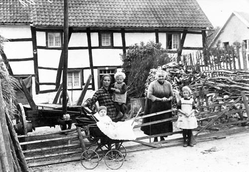 Familie Breuer 1927 im Hof von Muue. ber dem Brennholz rechts ist am Gartenzaun die Hhe des "Felshgels" zu erkennen.  Repro : DGKV